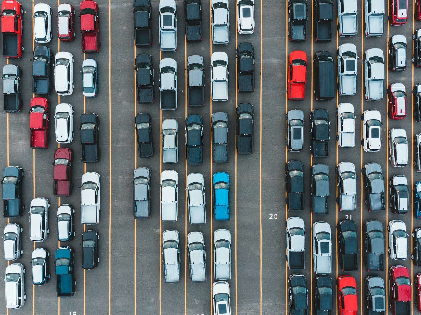 Muchos camiones y SUVs llenan un estacionamiento grande y ordenado.